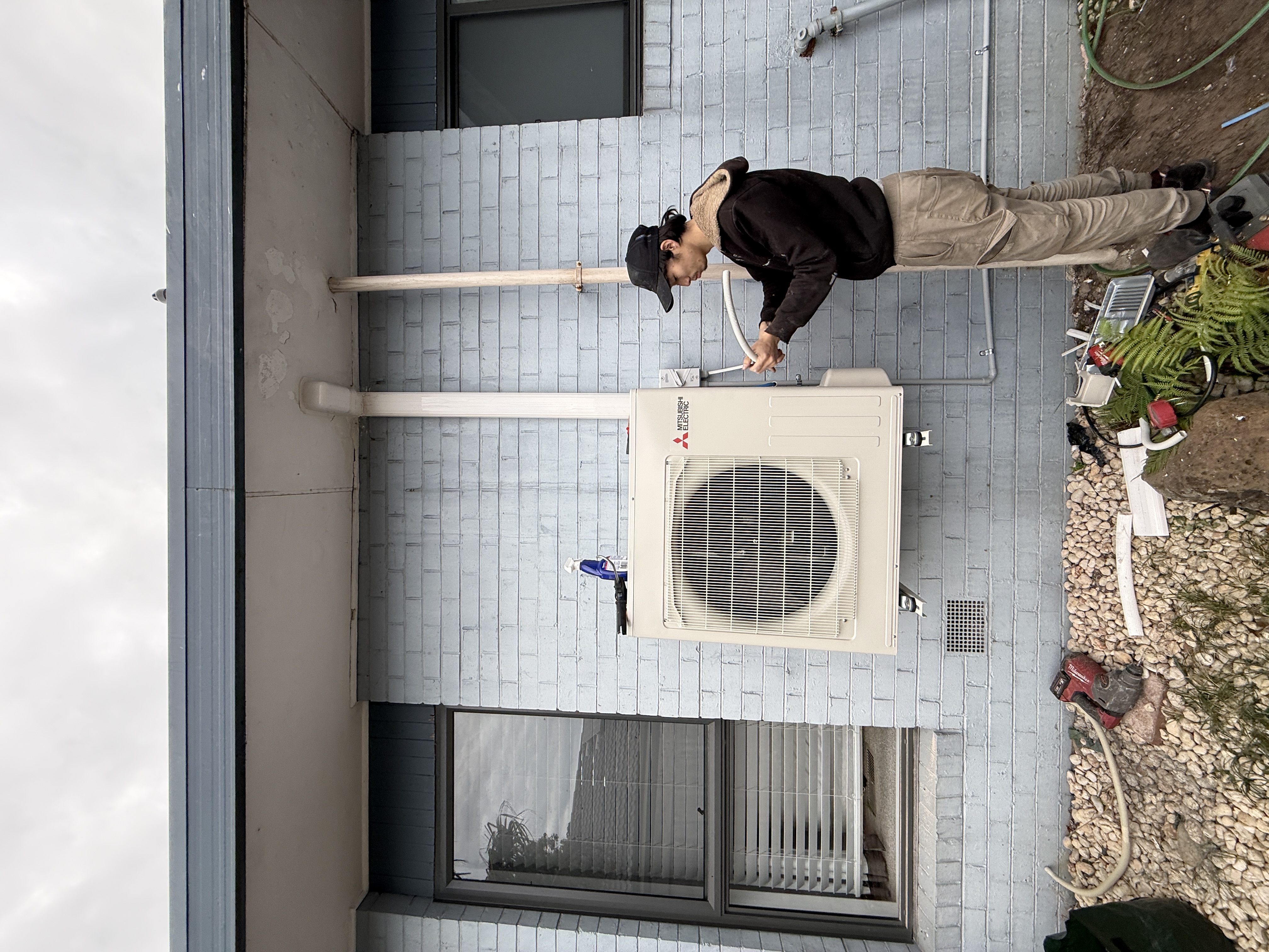 Person working beside a wall-mounted outdoor air conditioning unit